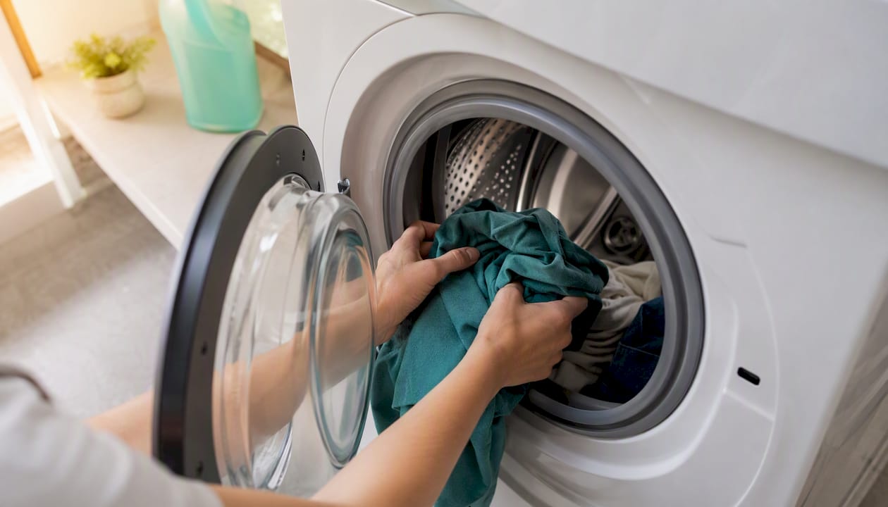 Cómo ahorrar energía en el hogar: 9 medidas clave 3 Manos colocando ropa dentro del tambor de la lavadora