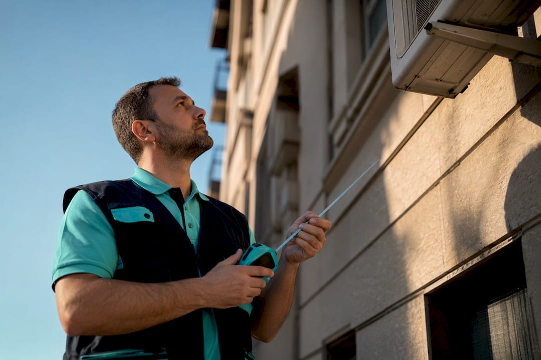 Técnico inspeccionando la unidad exterior en la fachada